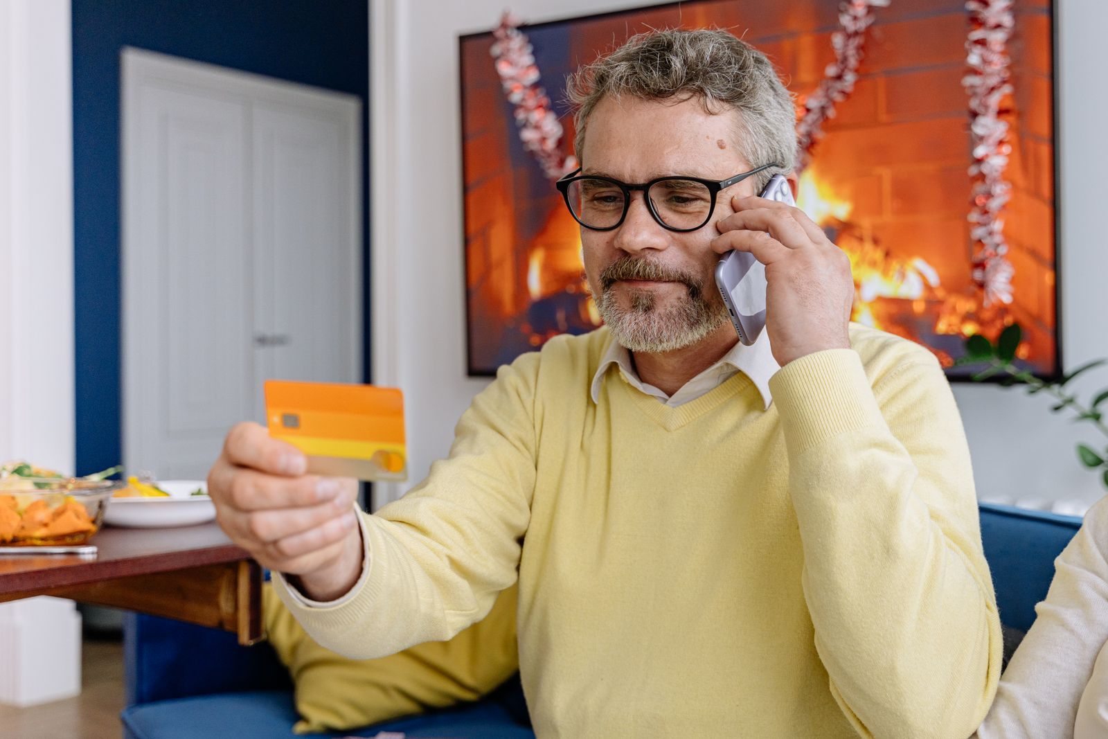 Man on the phone with a card in hand, ordering cruise deals from a TV channel