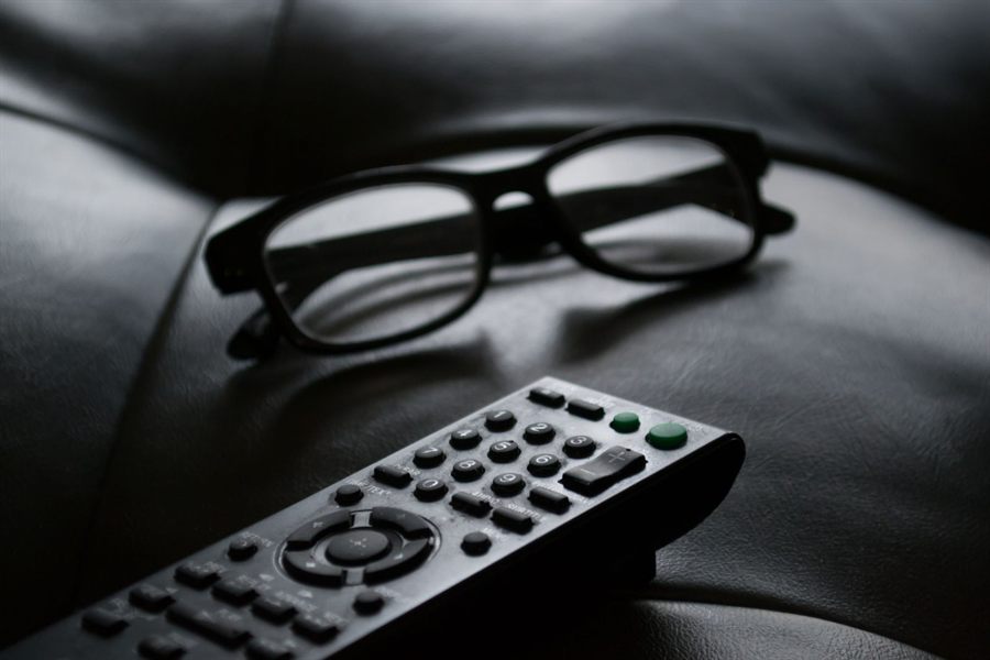 Reading glasses and a TV remote resting on a dark leather couch