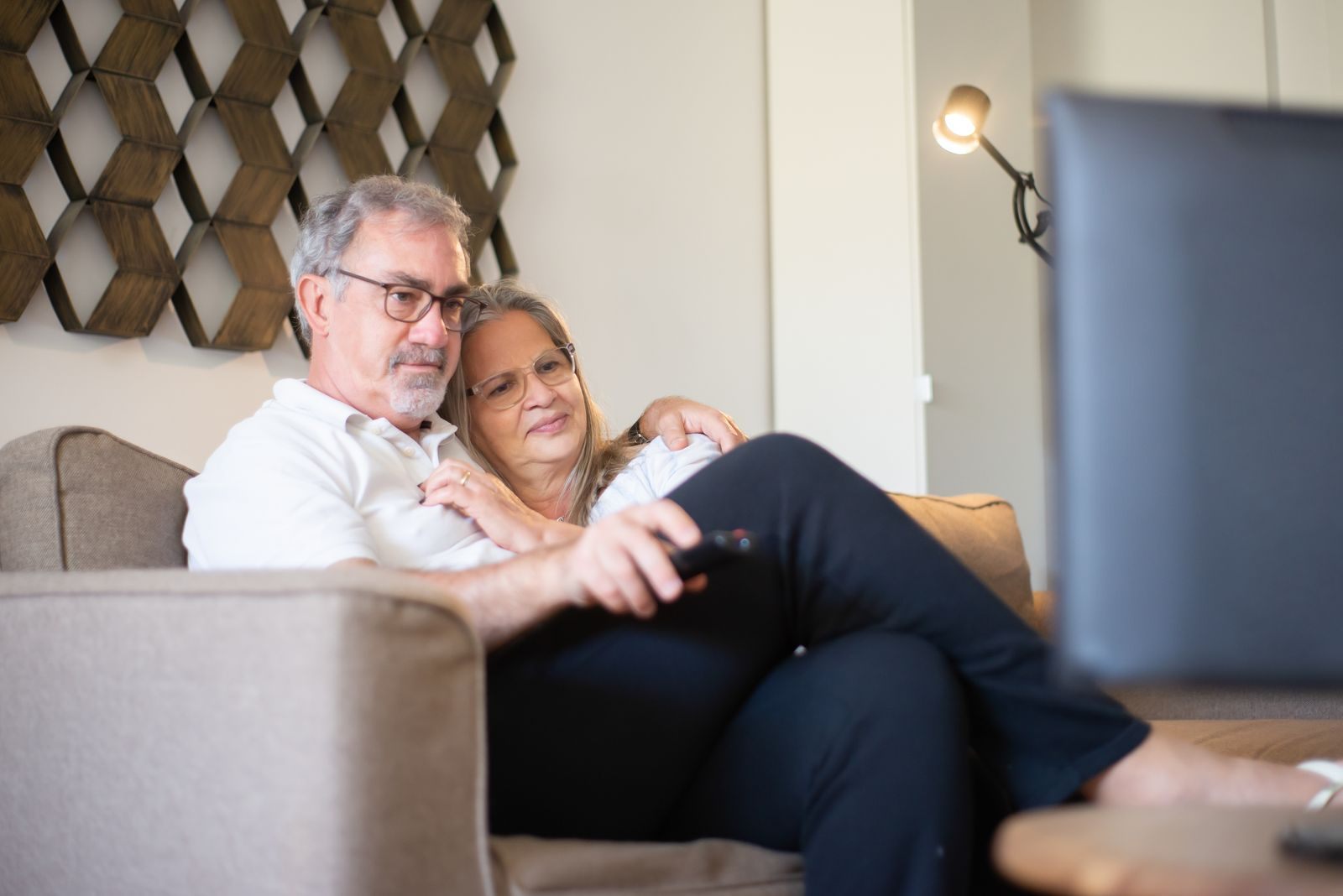 Senior couple relaxing on a sofa watching TV cruise deals together