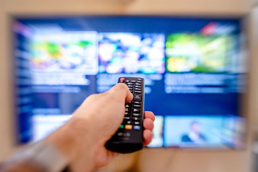 Remote control aimed at a blurred streaming menu on a TV screen