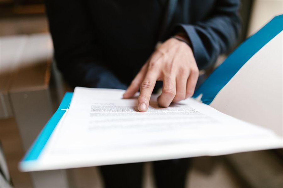 Hand pointing to a line of text on a printed document